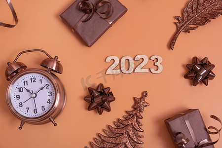 数字倒计时创意摄影照片_彩色背景上平躺的 2023 年新年数字，带闹钟和礼品盒顶视图