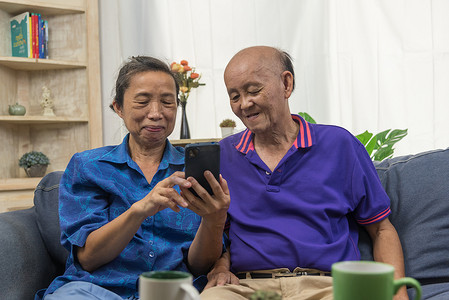 亚洲老人在家使用手机连接在线互联网通信技术。