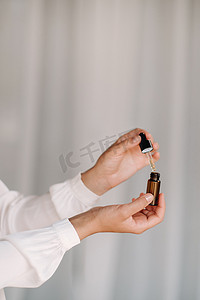 疗法摄影照片_拿着一瓶精油的女性手的特写，芳香疗法