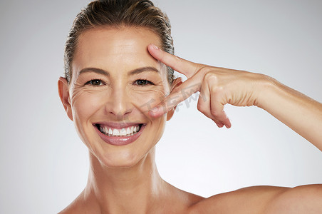 皮肤老化摄影照片_成熟女性的护肤、美容和面部护理，使用抗衰老产品来减少灰色样机工作室背景下的细纹和皱纹。
