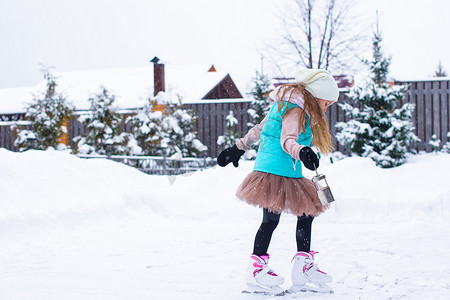 可爱的小女孩在冬雪天在户外滑冰