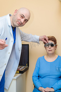 试镜摄影照片_男性验光师用试镜架检查成年女性的视力