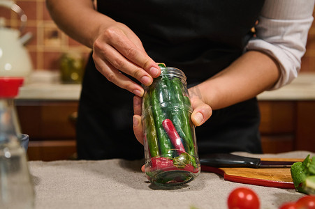 红绿辣椒摄影照片_细节：厨师的手拿着一个罐子，里面装满了新鲜有机红绿辣椒，准备腌制
