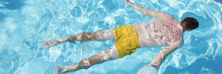 穿泳裤的男性腹部漂浮在水面上，池中清水