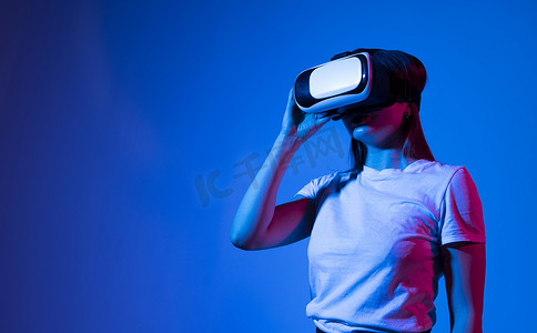 戴着 VR 护目镜的女人在工作室的元宇宙中放松并与朋友玩电子游戏。