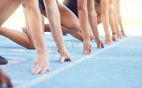 跑步者双手放在跑道上的起跑线上，准备跑步。
