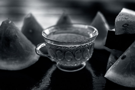 西瓜种子水果冰茶在木质表面的透明玻璃杯中，还有三角形的西瓜片。