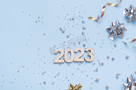 数字倒计时创意摄影照片_数字 2023 在明亮的节日背景与弓和珠顶视图。