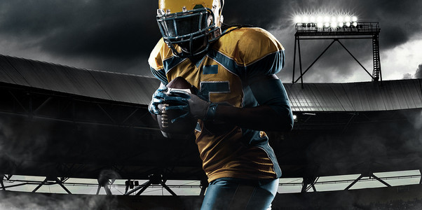 美国橄榄球运动员，戴头盔的运动员，在体育场上带球。