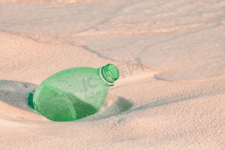塑料水瓶摄影照片_丢弃在海滩的塑料水瓶