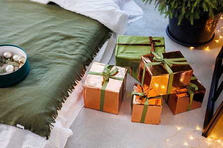 除夕夜背景摄影照片_除夕夜，圣诞树下的地板上放着纸制的新年礼物和鲜艳的丝带。