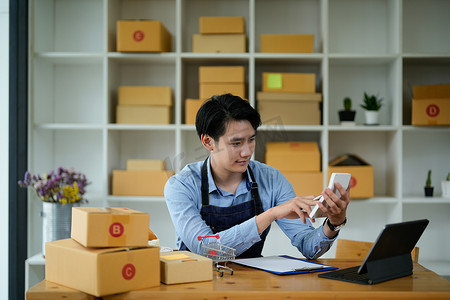 初创小型企业 SME，企业家所有者使用笔记本电脑接收和检查在线采购订单以准备包装产品盒。