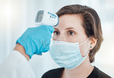 Covid、温度计和医生在医院扫描戴口罩咨询的妇女的发烧温度。