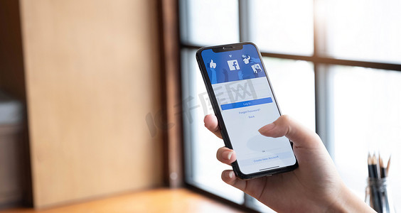 泰国清迈，2022 年 7 月 10 日：手持 iPhone X 的女性在屏幕上使用社交互联网服务 Facebook。
