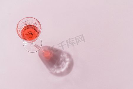 简约背景装饰图案摄影照片_粉红色背景的漂亮玻璃杯中的饮料的简约组合。