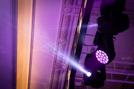 宴会厅摄影照片_带有摇头灯和舞台照明的 RGBW LED 聚光灯悬挂在宴会厅的天花板桁架上