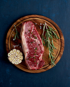 大整块生牛肉，深蓝色背景木切板上的西冷牛排