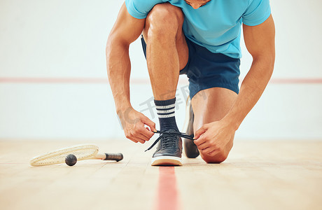 不打游戏摄影照片_不知名的运动壁球运动员在与复制空间打法庭游戏之前跪着系鞋带。