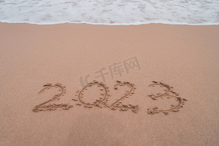 新年规划摄影照片_2023 年新年即将到来，背景是日落海滩。