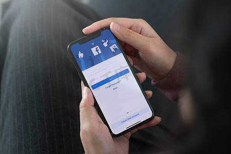 泰国清迈，2020 年 8 月 10 日：手持 iPhone X 的女性在屏幕上使用社交互联网服务 Facebook。