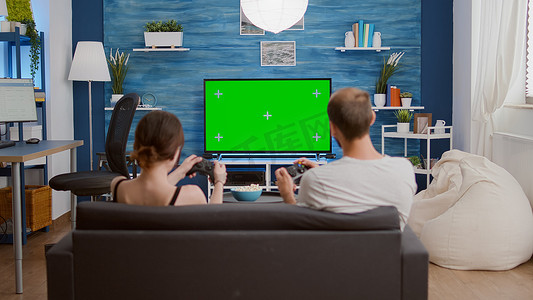 游戏钥匙摄影照片_几个玩家花空闲时间在绿屏上玩快节奏的控制台动作游戏