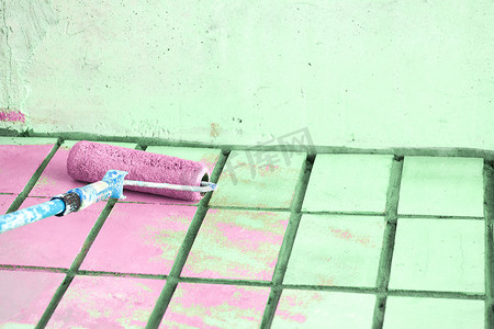 墙面艺术油漆摄影照片_用粉红色油漆滚筒涂绿色墙面