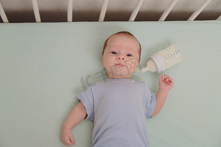 婴儿床顶视图中拿着瓶子的婴儿。