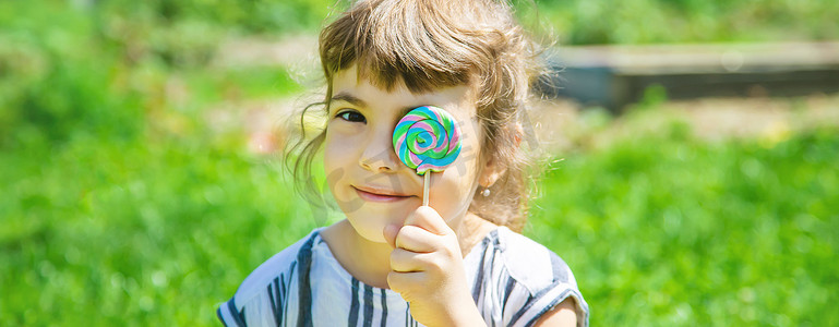 夏天吃糖摄影照片_孩子在大自然中吃棒棒糖。