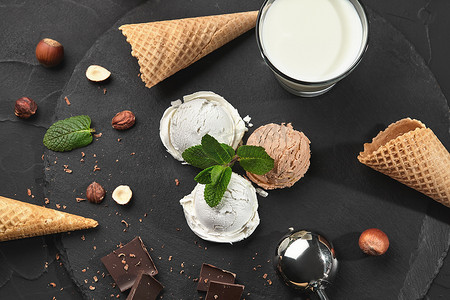黑色背景下的石板上供应美味的奶油和巧克力冰淇淋。