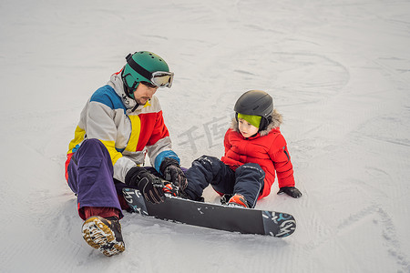 单板滑雪教练教男孩滑雪。