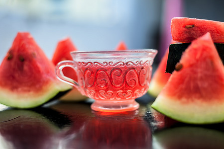 西瓜种子水果冰茶在木质表面的透明玻璃杯中，还有三角形的西瓜片。