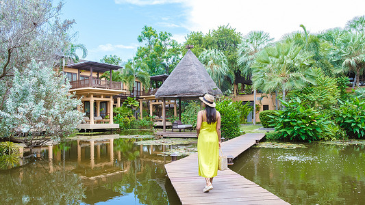 度假时戴帽子在热带花园散步的亚洲女性