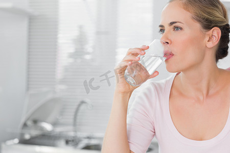 沉思的金发女人喝水