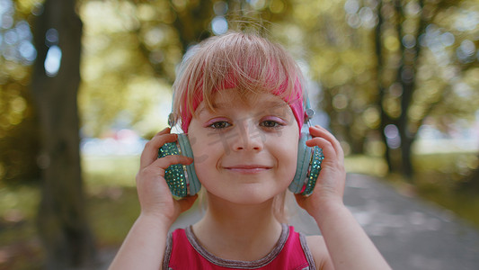运动健身运动跑步小女孩戴着耳机在公园里听最喜欢的音乐歌曲