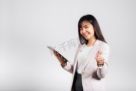快乐生活摄影照片_快乐生活方式的女青少年拿着数字平板电脑，竖起大拇指表示好兆头