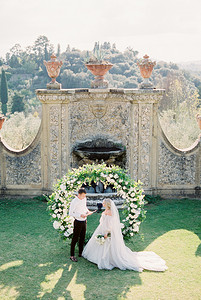 新郎在石墙前的婚礼拱门上向新娘宣誓