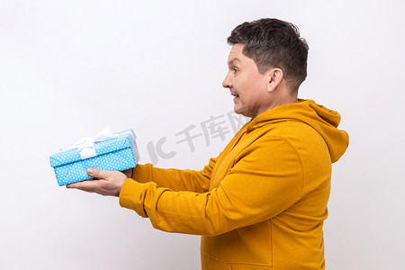 积极慷慨的男人微笑着送礼盒，分享节日礼物的侧视图。