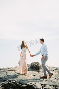 手拉手摄影照片_男人和女人手拉手走在悬崖上