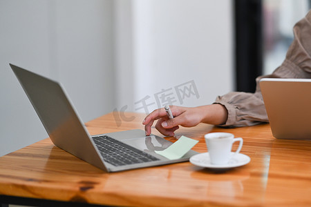 裁剪镜头的女人拿着笔记本和打字 o 笔记本电脑。