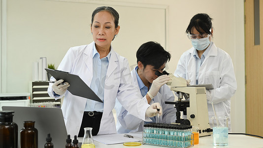 高级女科学家为科学报告和后台工作的实验室助理分析和总结信息