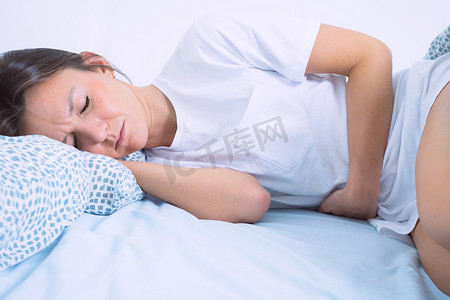 年轻女子躺在床上，患有妇科病、月经痛、胃痛或腹痛。