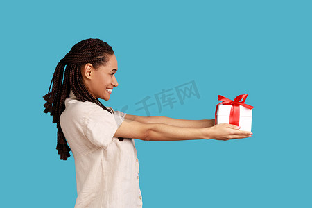 幸福的女人送礼物盒，看着相机，祝贺朋友生日的侧视图。