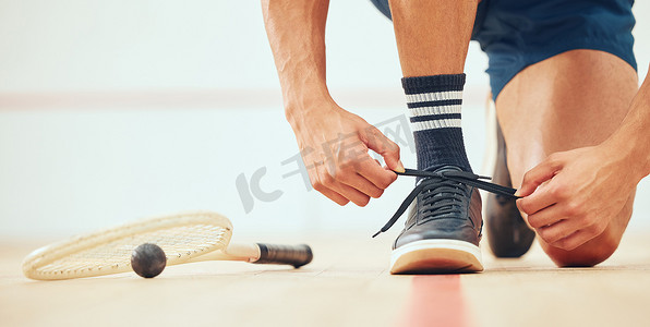 不打游戏摄影照片_不知名的运动壁球运动员在与复制空间打法庭游戏之前跪着系鞋带。