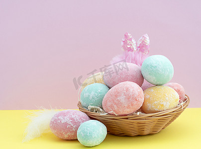 粉蓝色背景的柳条篮中，彩绘精致的彩绘复活节彩蛋和兔耳 库存图片