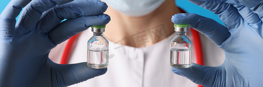 疫苗瓶摄影照片_科学家拿着两瓶注射液，戴着蓝色手套