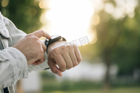 日落时分，男性在户外使用可穿戴智能手表的特写镜头。