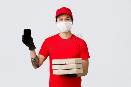 严肃的亚洲送货员展示智能手机屏幕，带食品客户上门，显示订单信息，快递员带披萨，确认细节，推荐奖金申请，戴医用口罩