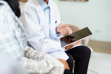 一位医生拿着平板电脑工作并与前来治疗的患者交谈，为客户提供健康问题建议的肖像