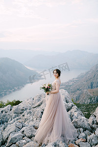 石子落下摄影照片_新娘站在科托尔湾背景下的落基山上
