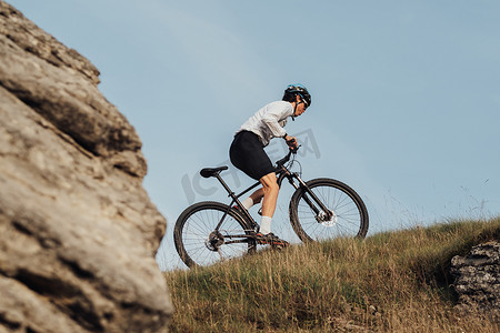健康生活方式摄影照片_专业山地自行车骑手在日落时在山上骑行，户外极限运动，积极健康的生活方式